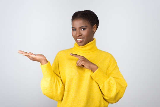 Content Young Woman Showing Copy Space. Beautiful Young African American Woman Pointing Aside With Finger And Smiling At Camera Isolated On White Background. Advertisement Concept