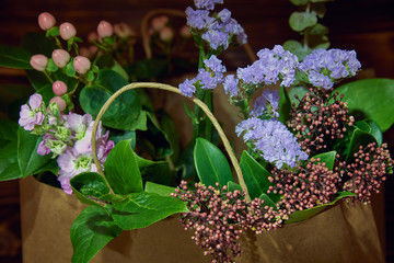Delicate flowers and branches with green leaves in a paper bag