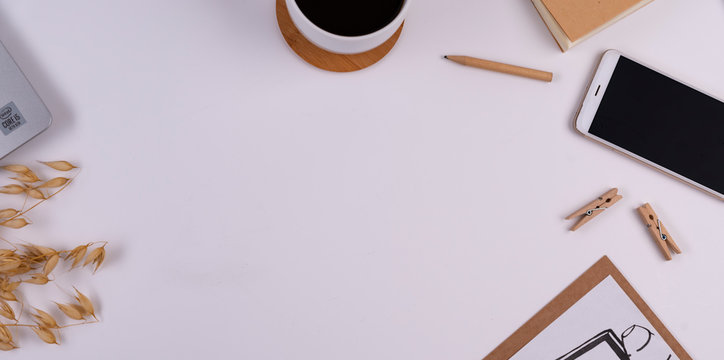 Design office desk on white background with copy space. Wooden accessories, laptop, picture , smartphone and cup of coffee. Banner and top view.