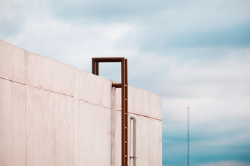 Steel staircase for climbing up to the roof against a cloudy sky background