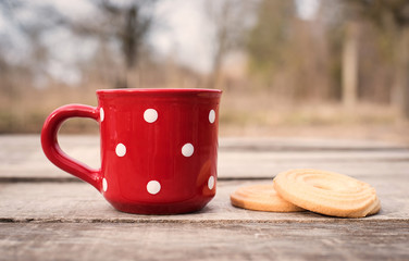 Dark tea in a red polka dot mug with biscuit