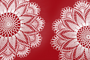 Two handmade crocheted white lace napkins isolated on red background