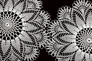 Two handmade crocheted white lace napkins isolated on black background