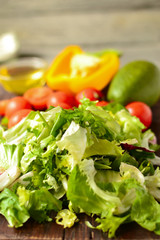 Ingredients for vegan spring and summer salad. Vegetables on a cutting board. Tomatoes, sweet yellow pepper, lettuce, dressing, avocado, oil in a bowl.