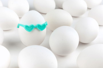conceptual photo of individuality love. egg in glasses in form of hearts among other eggs