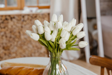  White tulips in a vase in a rustic interior