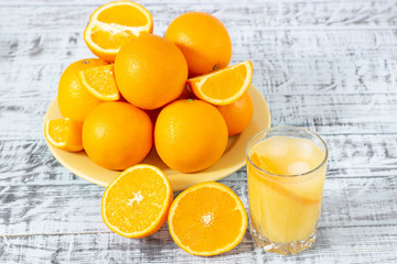 Freshly squeezed orange juice. Glass of orange juice and a plate with oranges on a wooden table.