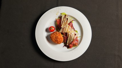 Carpaccio with potato patty, parmesan and cherry tomato.     