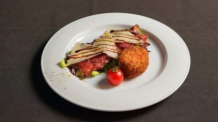 Carpaccio with potato patty, parmesan and cherry tomato.     