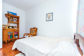 Prayer bedroom with a large double wooden bed, rocking chair and many Christian icons in the sideboard opposite the bed