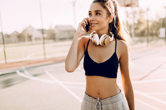 Image of a young athletic woman, outdoors, talking on a mobile phone,