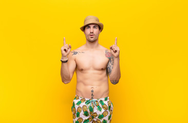  looking shocked, amazed and open mouthed, pointing upwards with both hands to copy space