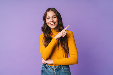 Image of young beautiful woman smiling and pointing finger at copyspace