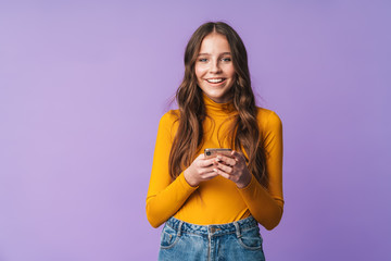 Image of young beautiful woman smiling and holding cellphone