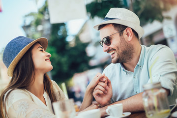 Beautiful loving couple sitting in a cafe enjoying in coffee and conversatio