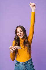 Image of young beautiful woman rejoicing and holding cellphone