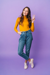 Full length image of beautiful woman smiling and gesturing peace fingers