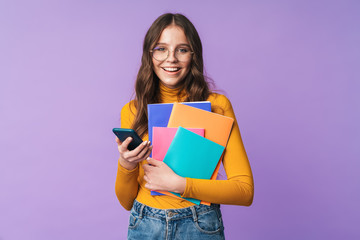 Image of young student girl holding exercise books and cellphone