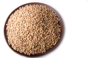 Raw green lentils in a plate? on a white background.