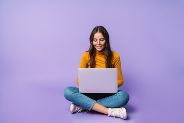Image of young woman using laptop while sitting with legs crossed