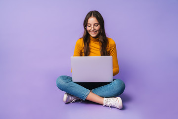 Image of young woman using laptop while sitting with legs crossed