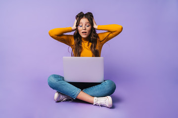 Image of young woman using laptop while sitting with legs crossed