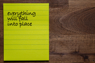 yellow sticker with lines on a dark wooden background with the handwriting of the wisdom of life:...