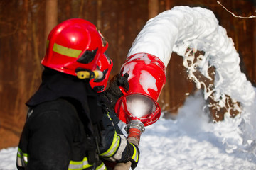 Firefighters extinguish a fire. Rescuers with fire hoses with foam.