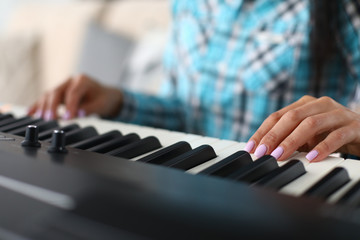 Musician fingers on flat keys synthesizer surface. Girl gets used to force pressing to extract...