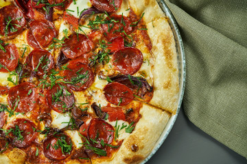 Top view on Appetizing pizza with spicy chorizo salami on wooden background in a restaurant. Italian cuisine.