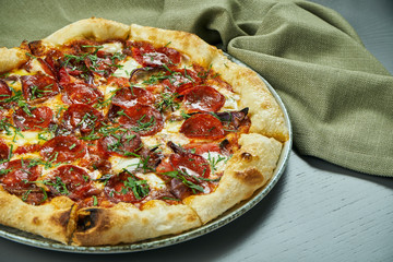 Appetizing pizza with spicy chorizo salami on wooden background in a restaurant. Italian cuisine. Close up, selective focus