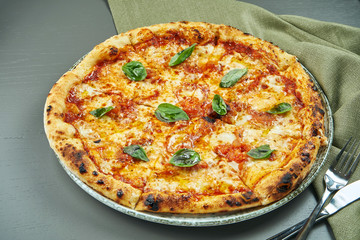 Top view on Appetizing pizza margherita with tomatoes and basil on wooden background in a restaurant. Italian cuisine.