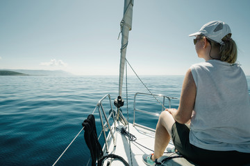 Woman sitting on the ships bow enjoying the yacht trip. Sailing, yachting and travel concept.