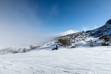 Fototapeta na wymiar Snowboarder sitting facing foggy hill.