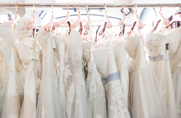 Beautiful, White bridal dress texture on background. Wedding dresses hanging on a hanger interior of bridal salon. Design, fashion modern luxury in detail.