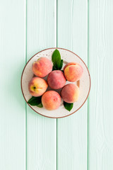 Summer fruits. Ripe red peaches on plate on green wooden table top-down copy space