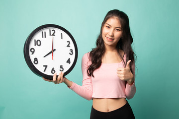 Young Asian woman thumbs up with a clock.