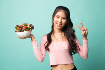 Healthy Asian woman show victory sign with salad.