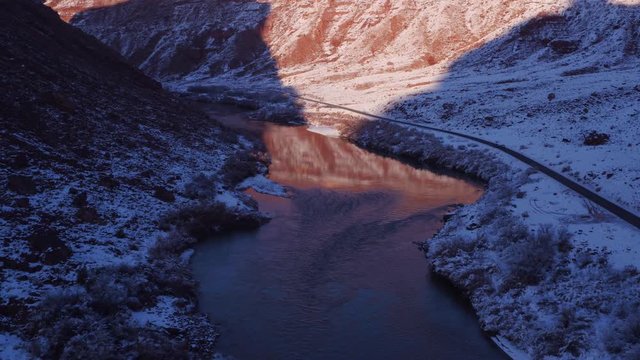 Aerial Footage of Colorado River and Reflections in Winter Near Moab, Utah U.S.A. Following Cars Approaching Flyover Below by Drone