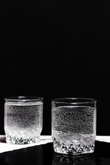 Glasses with mineral water on a white table against black background.