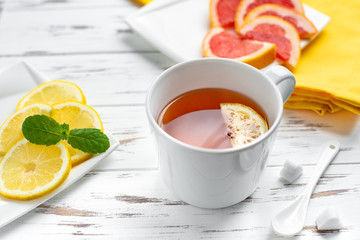 cup of black tea with lemon and grapefruit , close up on the white wooden background