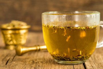 herbal tea with mortar with herbs in the background