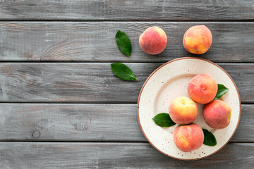 Summer fruits. Ripe red peaches on plate on dark wooden table top-down copy space