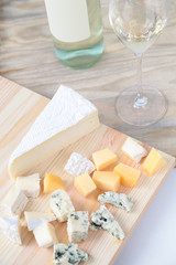 Bottle of white wine two glasses and cheese on a wooden board