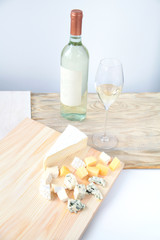 Bottle of white wine two glasses and cheese on a wooden board