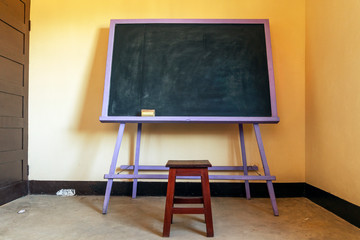 Classic blackboard with a wooden chair in a yellow classroom