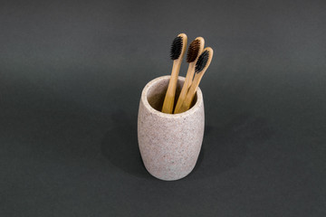 Eco toothbrushes in a glass on grey background