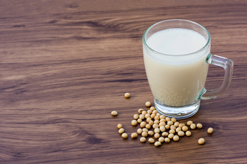 Glass of soy milk with soybeans  isolated on wood table background. Healthy drinks concept.