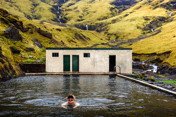 Young boy swims in the Seljavallalaug geothermal pool located in south Iceland. This outdoor pool...