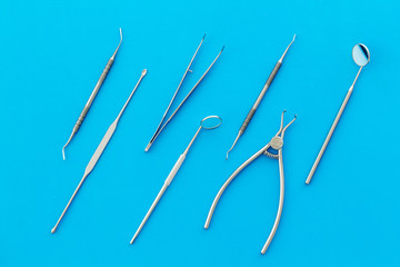 Stomatological tools on dentist's desk on blue background top-down pattern